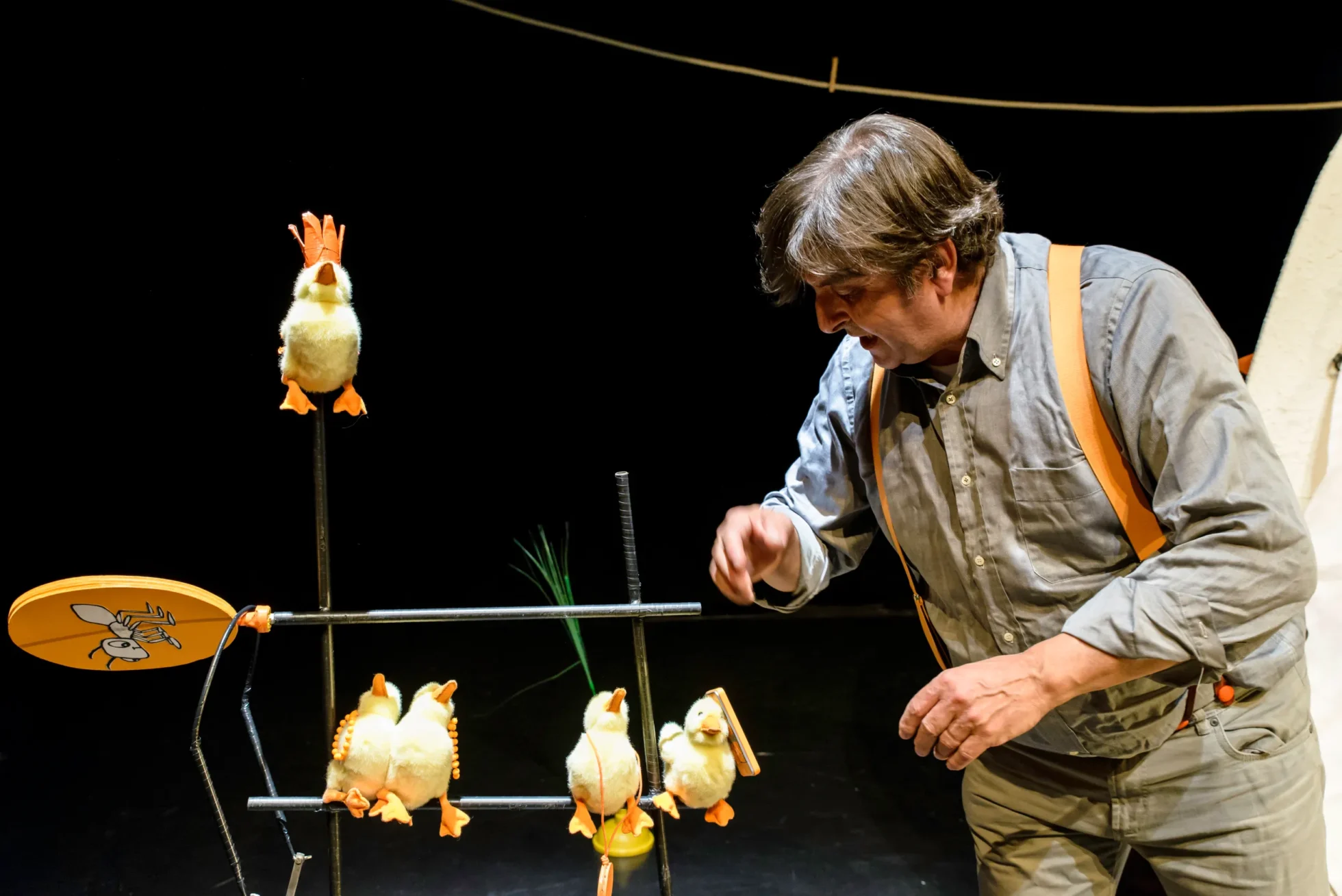 attore in scena con dei pupazzi a forma di papera