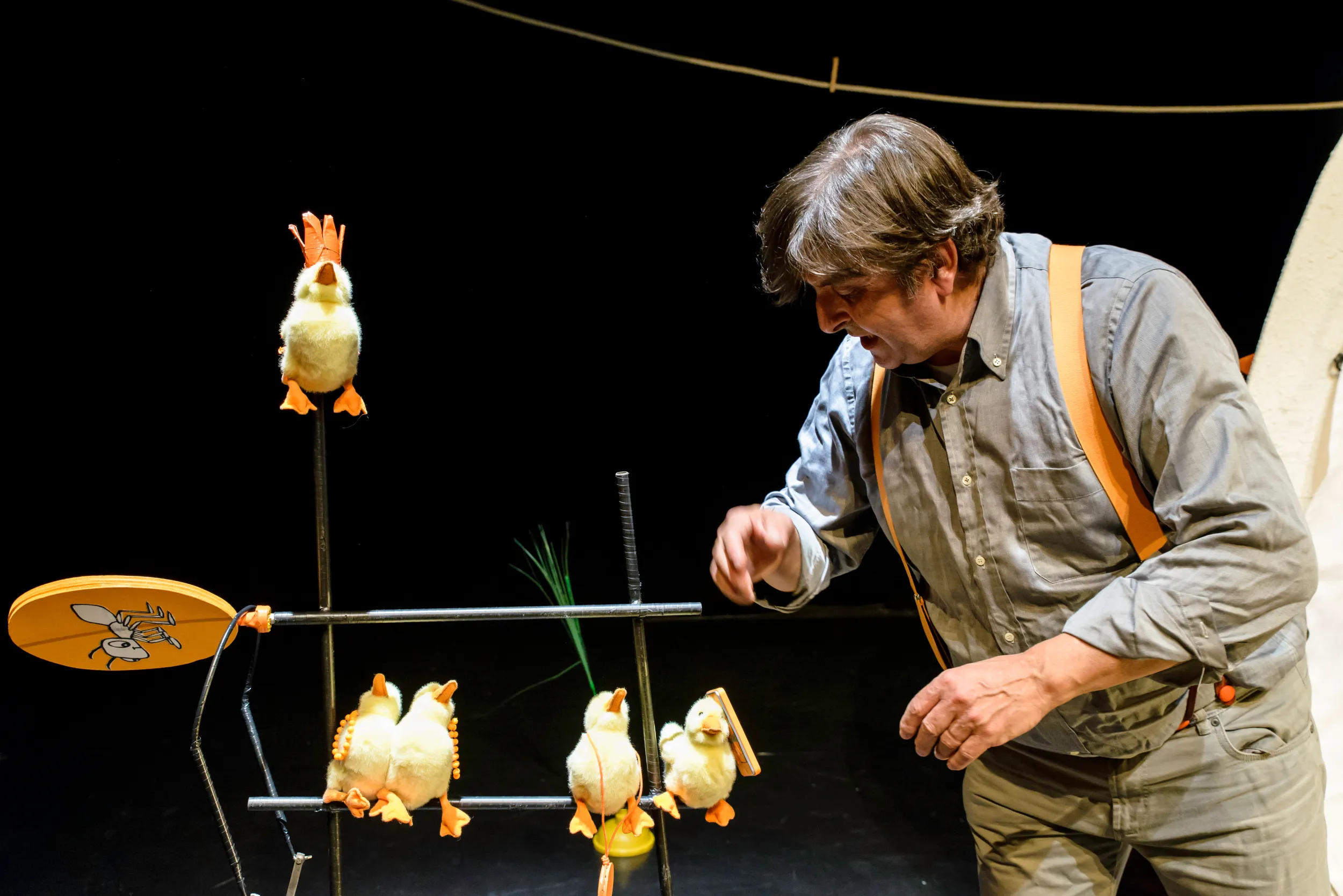 attore in scena con dei pupazzi a forma di papera