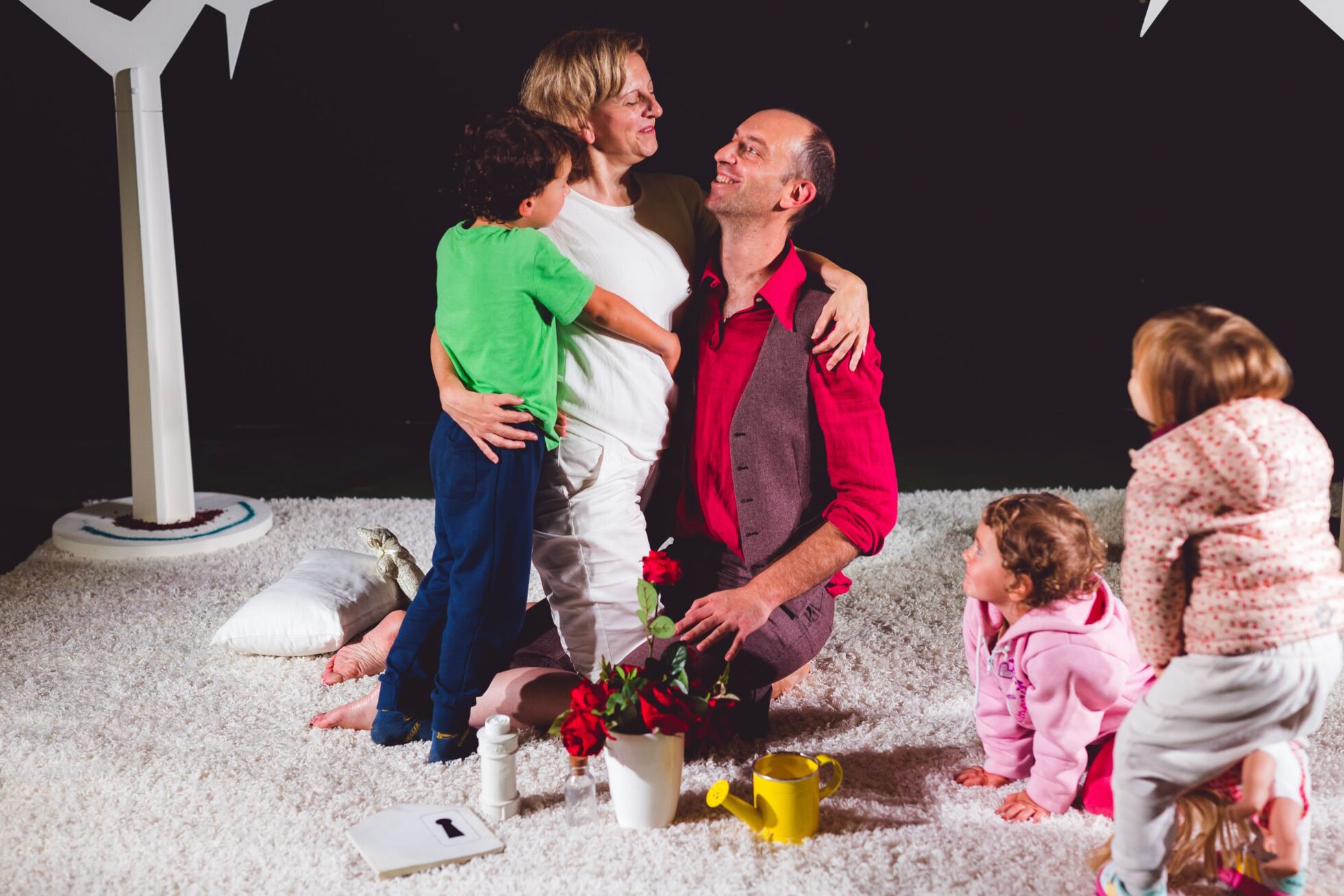 Due attori maschio e femmina si abbracciano assieme ad un bambino del pubblico alla fine dello spettacolo