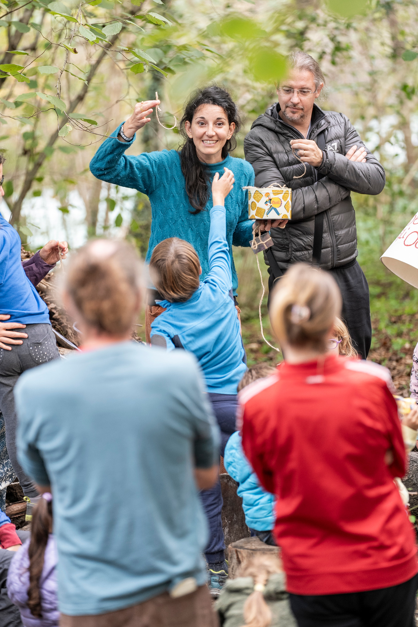 Un'attrice che coinvolge il pubblico di bambini seduti nel bosco