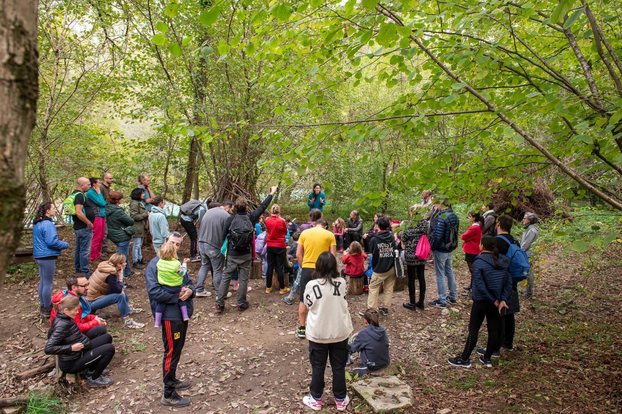 pubblico di bambini e genitori che assistono ad uno spettacolo nel bosco
