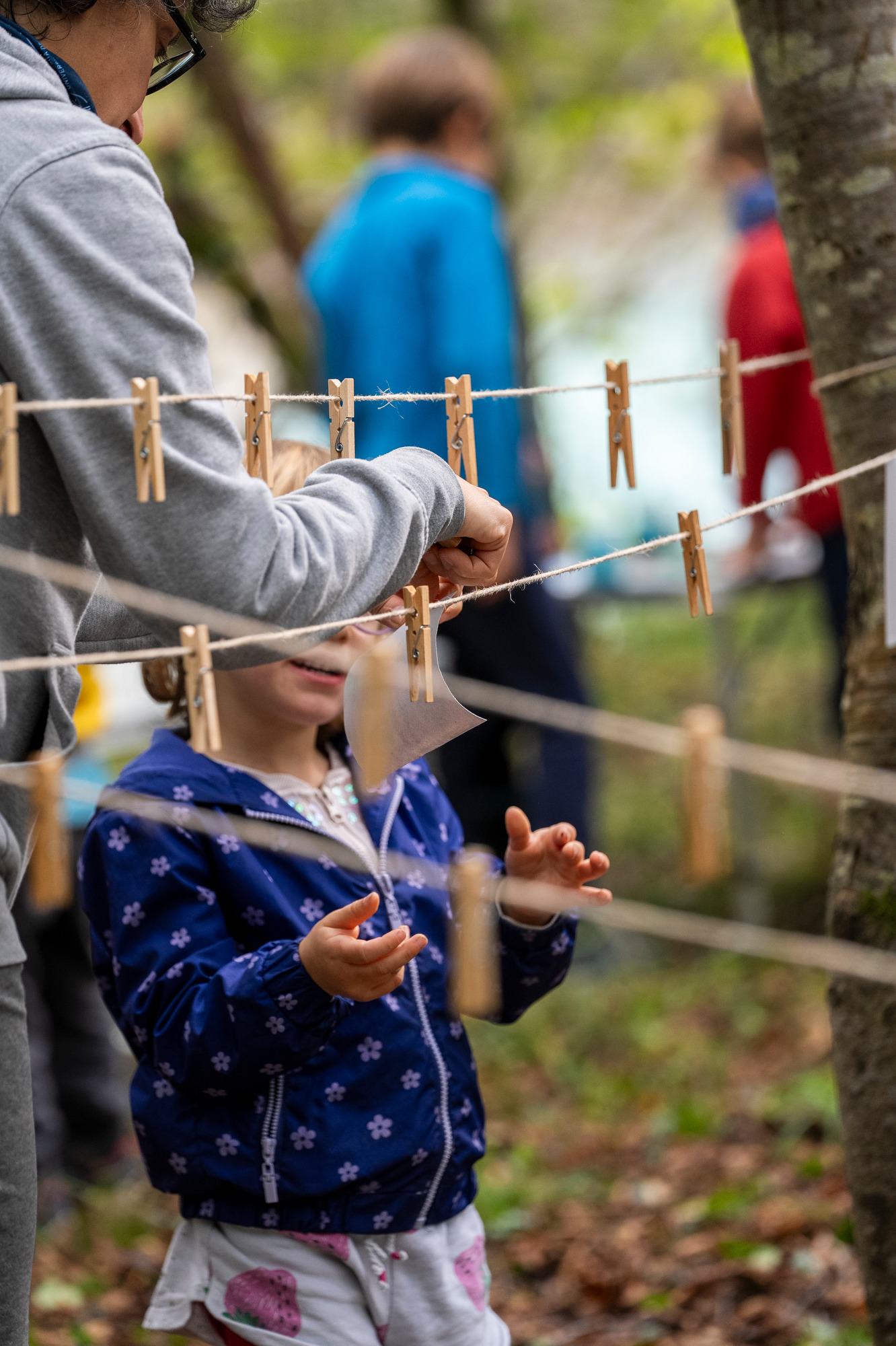 Bambina appende nel bosco una sua creazione artistica