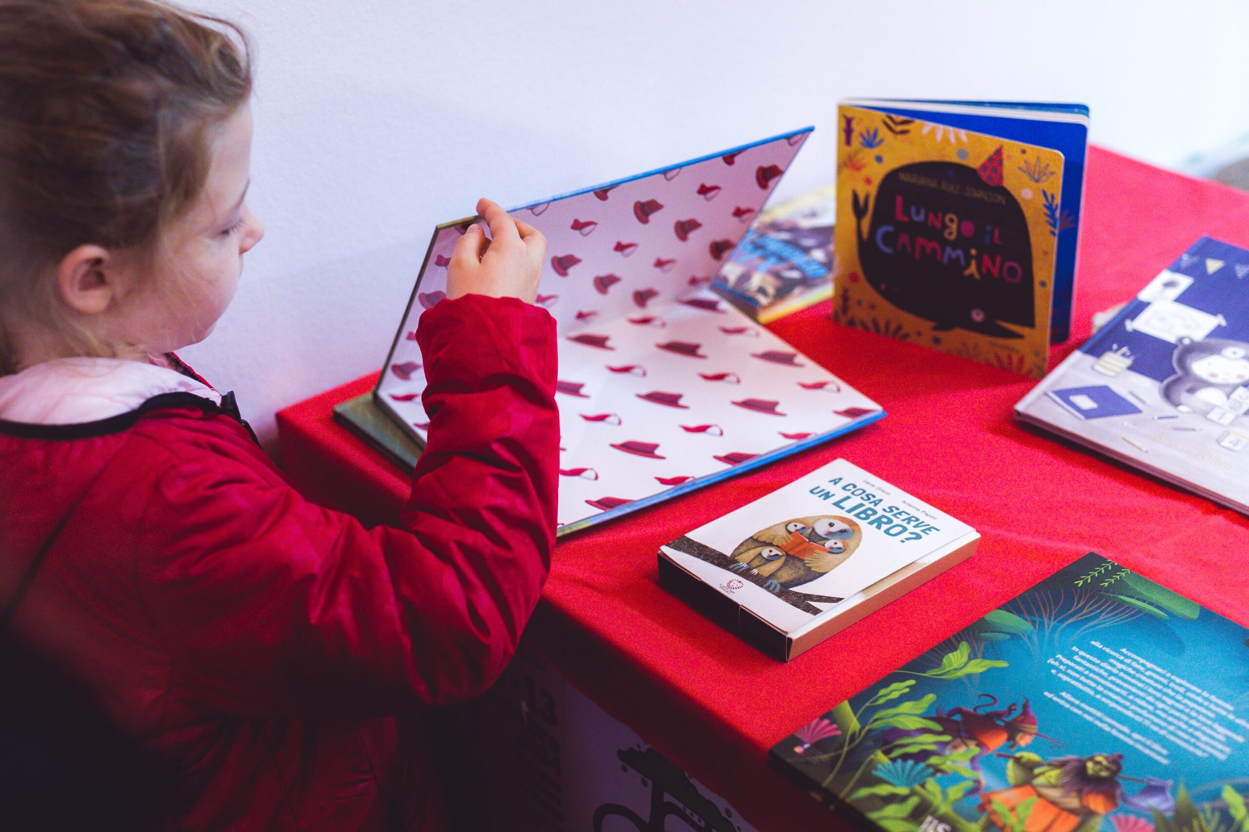 bambina apre un libro nella bancarella dei libri esposta al festival Trallallero