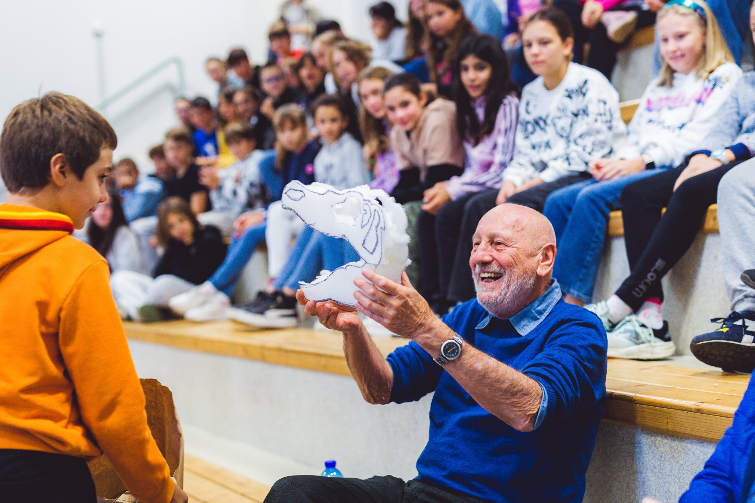 l'autore sorride seduto fra il pubblico di studenti a scuola