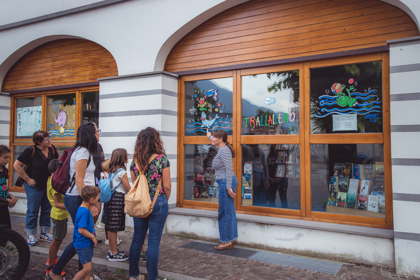 Artista spiega ai bambini con i genitori il suo disegno dipinto sulla vetrina