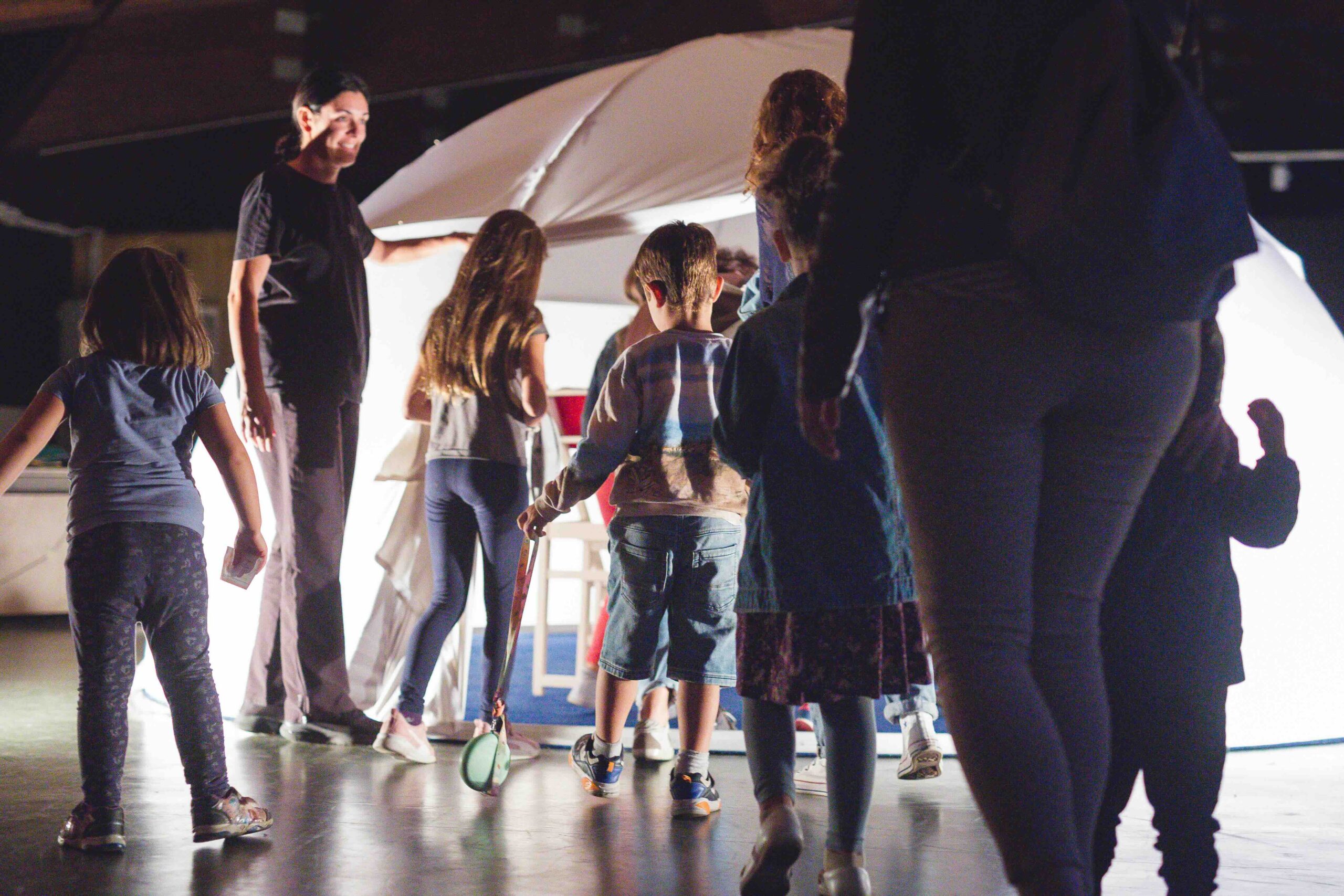 Famiglie che accompagnano i figli a vedere uno spettacolo innovativo all'interno di una tenda rotonda