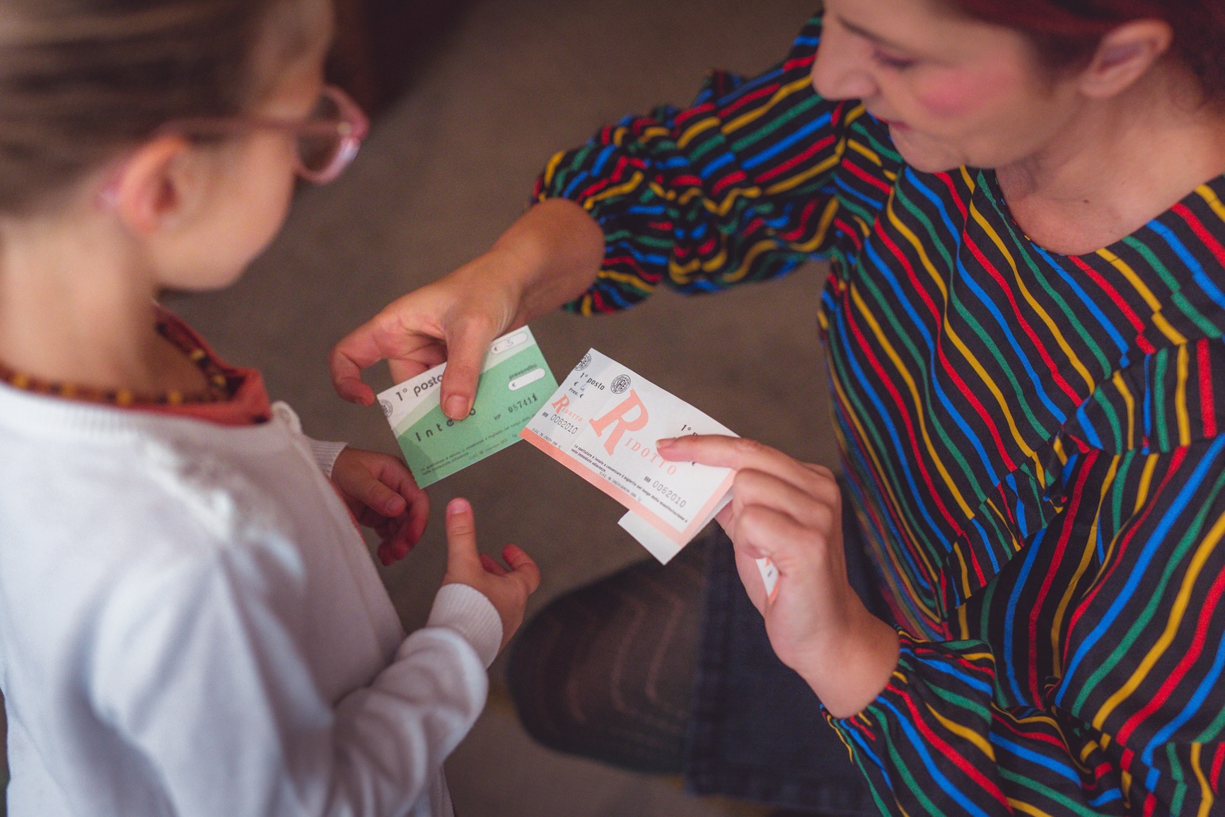una donna che consegna il biglietto per uno spettacolo teatrale ad una bambina
